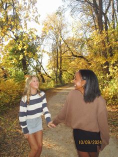 two women walking down a dirt road holding hands