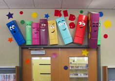 an office cubicle decorated with colorful crayons and paper faces on the wall