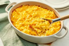 a casserole dish is shown with a spoon in it and plates on the side