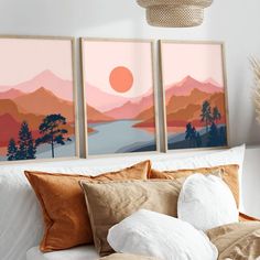 three paintings hang on the wall above a bed with pillows and throw pillows in front of it