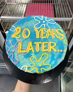 a birthday cake with the words 20 years later written in yellow and blue icing