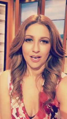 a woman with long brown hair wearing a red and white top is looking at the camera