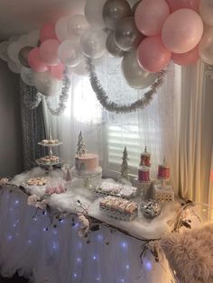 a table topped with lots of pink and silver desserts next to a window covered in balloons