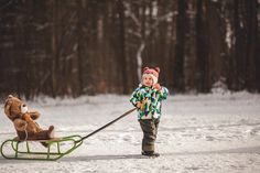 a small child pulling a teddy bear on a sled