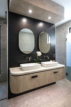 two sinks in a bathroom with mirrors and lights on the wall above them are white flowers