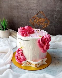 a birthday cake decorated with pink flowers and a happy birthday sign on the top tier