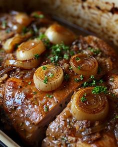 some meat with onions and garlic on it in a casserole dish, ready to be eaten