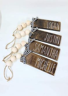 three wooden signs are hanging from a string on a white tablecloth with black and white gingham ribbon