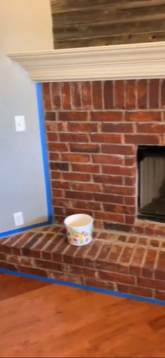 a brick fireplace with a cup on the mantle and blue tape around the fire place