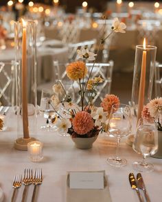 the table is set with silverware, candles and flowers in vases on it