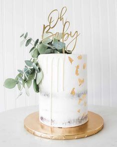 a white and gold cake with greenery on top