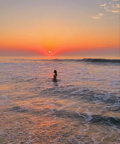 a person swimming in the ocean at sunset