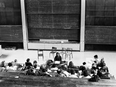 an old black and white photo of people sitting in front of a chalkboard