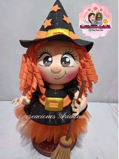 an orange and black witch doll with a broom