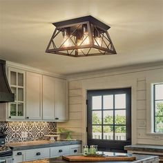 a kitchen with white cabinets and an island in front of a window that has lights hanging from the ceiling