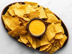 tortilla chips on a plate with a small bowl of dip in the middle