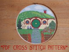 a cross stitch pattern with a house on the hill