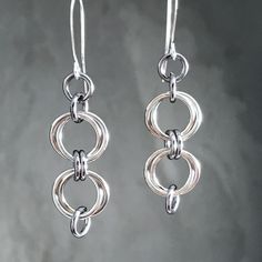 "A simple little twist on basic hoops! These are my everyday earrings. Really, I wear these all the time, and you will too!  Each earring consists of a double set of intertwined bright silver aluminum loops connected with gunmetal gray links.  *  2 inches long *  lightweight aluminum *  elongated silver plated ear wires *  hypoallergenic The elongated ear wires of silver plated brass are lead and nickel free. Aluminum is non tarnishing, so these earrings will always stay bright and shiny. The gunmetal colored rings are aluminum that has been anodized; the colored coating is very durable and will not tarnish or fade. If you have any questions regarding these gorgeous earrings, please contact me using the \"Message Seller\" button and I will get right back to you. Thanks for shopping at Twis Cadmium-free Metal Earrings For Everyday Wear, Simple Metal Jewelry For Pierced Ears, Handmade Jewelry With A Modern Look, Minimalist Cadmium-free Dangle Earrings, Handmade Jewelry With A Modern Twist For Everyday, Simple Nickel-free Metal Earrings, Silver Jewelry With Jump Ring For Everyday, Simple Nickel Free Metal Jewelry, Simple Nickel-free Metal Jewelry