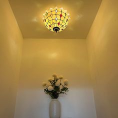 a vase filled with flowers sitting on top of a wooden floor next to a light fixture