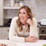 a woman sitting at a kitchen table smiling