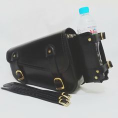 a black leather purse with a water bottle in it and a strap around the waist