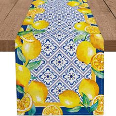 a table runner with yellow lemons and blue tiles on it, along with wooden boards