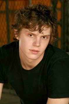 a young man sitting in front of a fence with his hands on his hips and looking at the camera