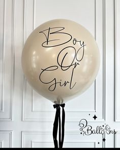 a white balloon with the words boy or girl written on it and a black ribbon