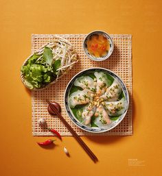 two bowls of food on a table with chopsticks and some vegetables next to it