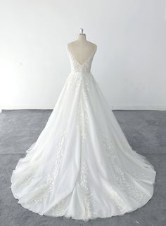 a white wedding dress on a mannequin in front of a white wall and floor