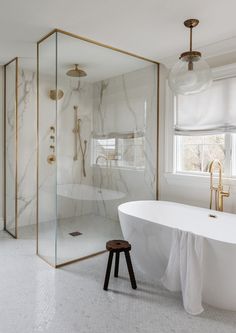 a white bath tub sitting next to a window in a bathroom with marble walls and floors