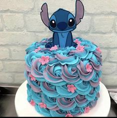 a cake with blue frosting and pink flowers on it, decorated like an elephant