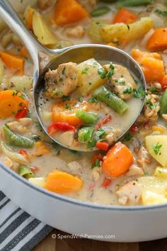 a ladle full of chicken and vegetable soup