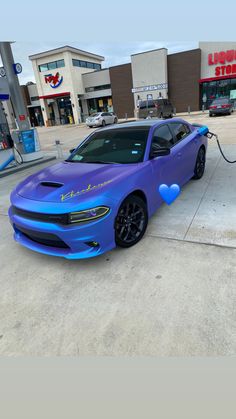 a blue dodge charger parked in front of a gas station with hearts painted on it