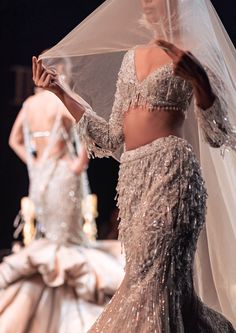 two women in wedding gowns and veils on the runway