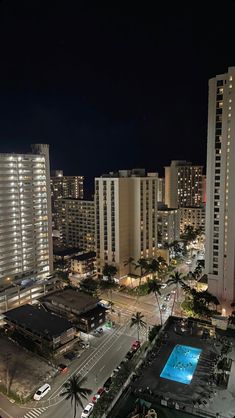 an aerial view of a city at night with cars parked in the parking lot and tall buildings