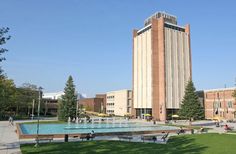 a large building with a pool in front of it and people sitting on the grass