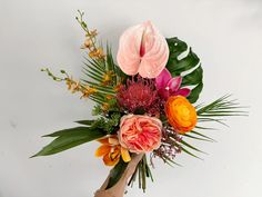 an arrangement of flowers is displayed on a white background with green leaves and pinks