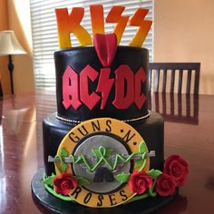 a black cake with red roses and letters on it sitting on top of a wooden table