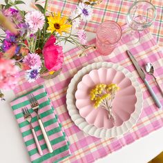 a pink plate with flowers on it sitting next to a fork and knife near a glass vase