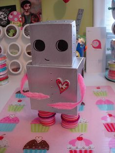 a robot made out of cupcakes sitting on top of a pink table cloth