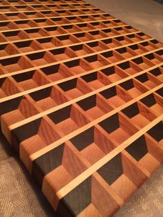 a large wooden cutting board sitting on top of a table with black and brown squares