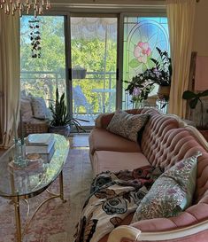 a living room filled with furniture and a chandelier above a glass top table