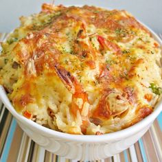 a casserole dish with cheese and vegetables in it on a striped place mat