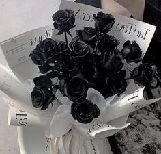 a bouquet of black roses sitting on top of a white plate with paper in it