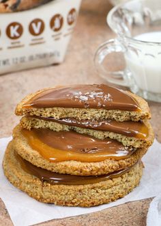 three cookies with peanut butter and chocolate frosting stacked on top of each other next to a glass of milk