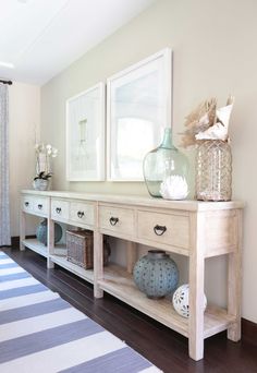 a white table with two vases on top of it next to a blue and white striped rug