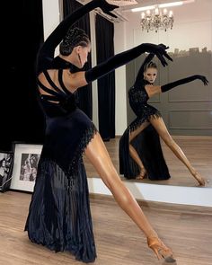 a woman in a black dress is dancing with her legs spread out and hands behind her back