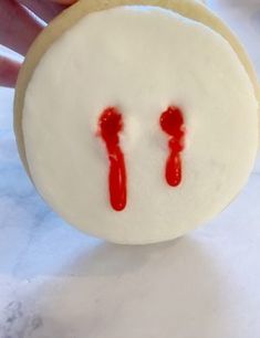 a cookie with red icing on it being held by someone