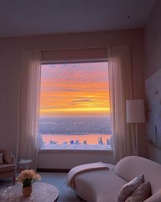 a living room with a large window overlooking the city and water at sunset or sunrise